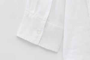 Detailed close-up of white linen shirt cuff showing natural fabric texture and stitching