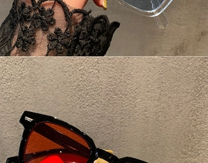 Detailed macro view of black square sunglasses with orange lenses and silver V metal accent