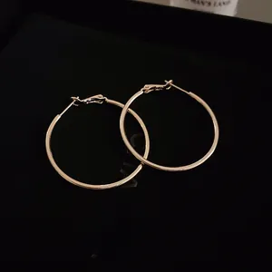 Close-up of gold geometric hoop earrings with polished finish and secure snap closure