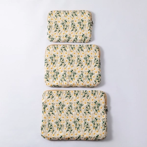 Detailed set of three beige quilted laptop sleeves featuring delicate daisy embroidery