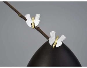 Macro detail of bicolored butterfly stud earrings with silver wings and golden body