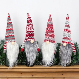 Set of four knitted Christmas gnome wine bottle covers with Nordic patterns on wooden shelf