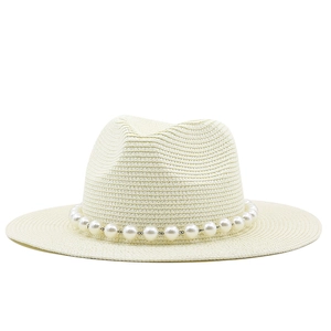 Detail of flat top straw fedora featuring elegant white pearl chain trim and woven texture