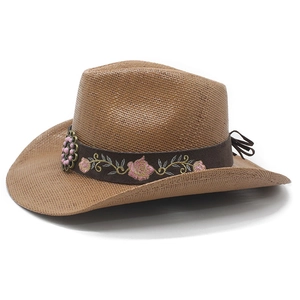 Detail of a brown woven straw cowboy hat featuring floral embroidery and metal accents