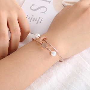 Detail of rose gold wire cable bracelet with moon, star charms and white pearls