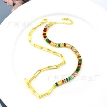 Close-up of gold chain necklace with colorful baguette zircons and paperclip links