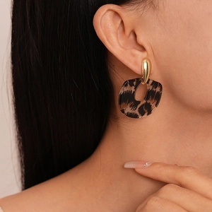 Gros plan d'un modèle portant des boucles d'oreilles en résine léopard et métal doré