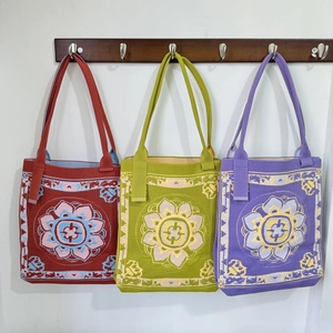Ethnic knit tote bags with lotus patterns in rust red, green, and lavender colors