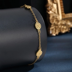 Detailed close-up of golden chain bracelet with circular hollow honeycomb charms