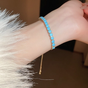 Détail du bracelet doré ajustable orné de pierres turquoises avec un fermoir coulissant
