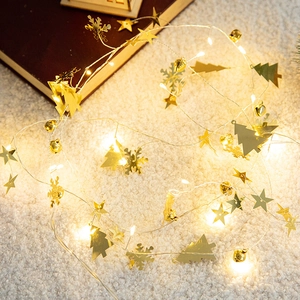 Christmas LED string lights with gold stars, snowflakes and bells on white plush carpet