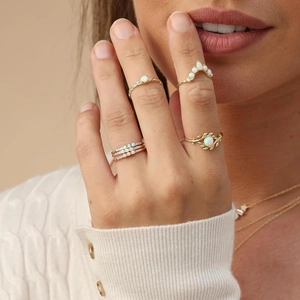 Detail view of gold opal rings set featuring leaf and crown designs on model hands
