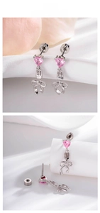 Detail of pink heart crystal earring with fork and bow pendant on a white soft surface