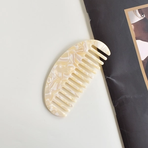 Cellulose acetate hair comb with cream marble pattern in a crescent shape