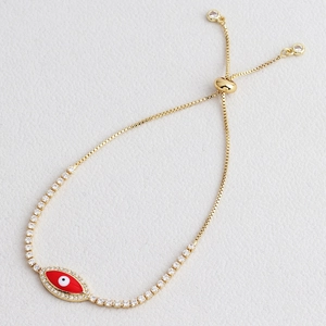 Macro shot of gold-plated tennis bracelet with red enamel evil eye and sparkling zircon