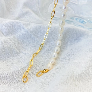 Detailed close-up of golden paperclip chain mixed with natural white freshwater pearls
