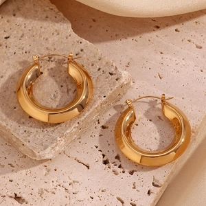 Macro di orecchini a cerchio placcati oro 18K su pietra e sfondo di seta liscia