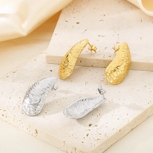 Detailed view of irregular hammered gold and silver stud earrings on a stone background