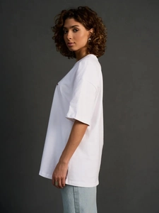 Κοντινό πλάνο λευκού oversize βαμβακερού t-shirt με μικρό κόκκινο κεντημένο λογότυπο