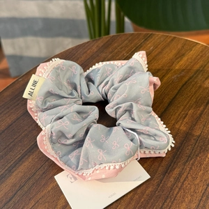Detailed view of grey hair scrunchie with pink bows and delicate white lace trim