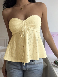 Detail of light yellow eyelet embroidery cotton tube top with drawstring bow and ruffles