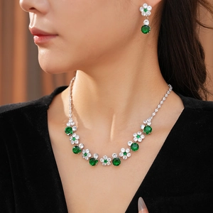 Close-up of emerald green flower necklace and earring set on model in black outfit