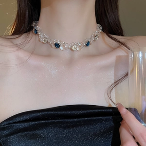 Close-up of beaded choker necklace with blue heart crystal on model's collarbone