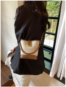 Close-up of beige canvas and brown PU leather bucket bag with metal buckle detail