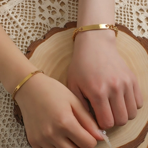 Detail of couple bracelets featuring polished gold rectangular bars and Cuban links