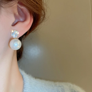 Close-up of elegant flower zircon earrings with a large round pearl on a model