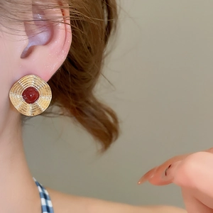 Makroaufnahme von Vintage-Goldohrringen mit rotem Stein und Spiralmuster-Textur
