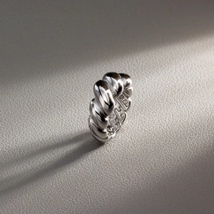 Macro shot of high-polished silver croissant ring with textured rope design and soft shadows
