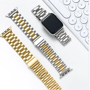 Detailed view of three-bead stainless steel watch bands in gold and silver on a desk