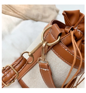 Detailed close-up of retro bucket bag showing cream canvas and brown leather stitching
