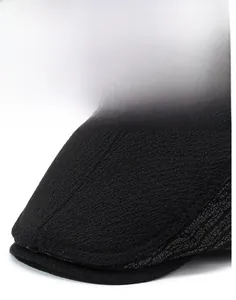 Detail of the stiff brim and knit texture on this black men's winter flat cap