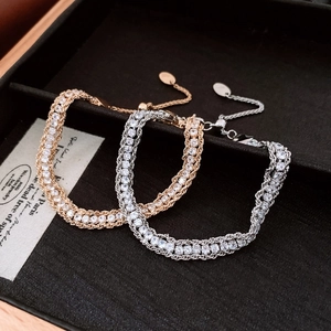 Detail of gold and silver interwoven chain bracelets with double-row inlaid zircons