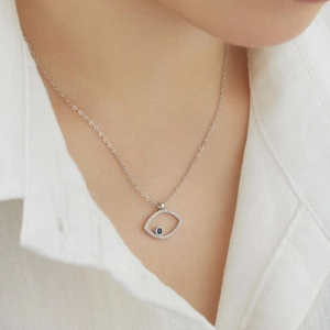 Macro shot of silver evil eye necklace with blue gemstone and diamonds on model