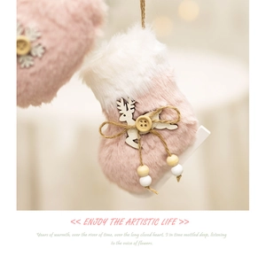 Close-up of pink and white plush angel ornament with wooden reindeer detail for Christmas tree