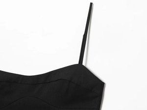 Détail des fines bretelles et de l'encolure d'une mini robe noire cintrée à la taille