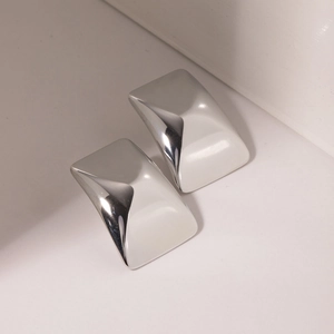 Macro view of polished silver square curved earrings with reflective metallic finish