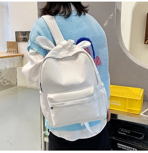 Rear view of a white bunny ear backpack with a minimalist design on a female model