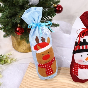 Christmas burlap wine bottle gift bags featuring reindeer and snowman designs near tree