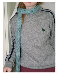 Detailed texture of thick knit light blue scarf paired with gray long-sleeve sweatshirt