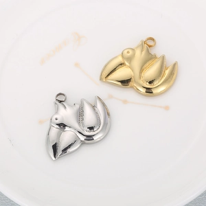 Gold and silver stainless steel pelican charms on a white plate for jewelry making