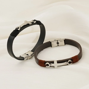 Dettaglio di bracciali in pelle con ciondoli a croce in acciaio inox e accenti di filo