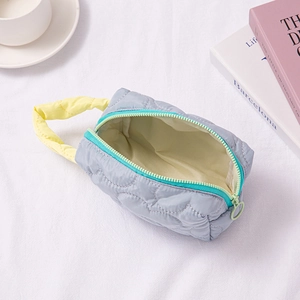 Detailed interior view of a gray quilted cosmetic bag with yellow handles and blue zipper