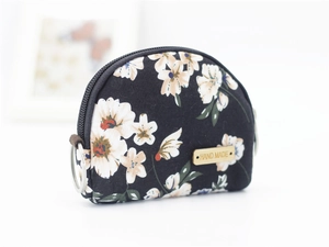 Macro detail of a semi-circular floral fabric coin purse with a wood Hand Made label