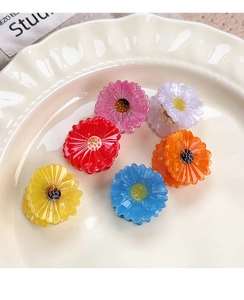 Detail of colorful acetate daisy flower hair claws displayed on a white ceramic plate