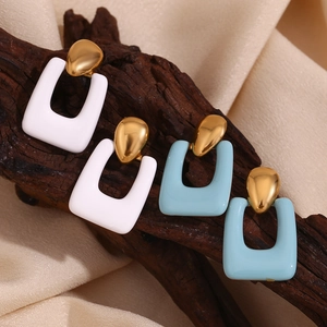 Detail of 18K gold-plated earrings with white and blue enamel on textured wood
