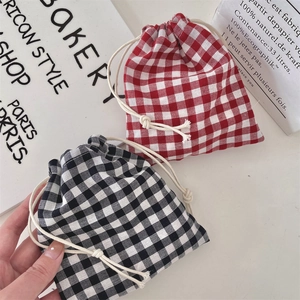 Close-up of red and black checkered drawstring pouches held in hand for size display